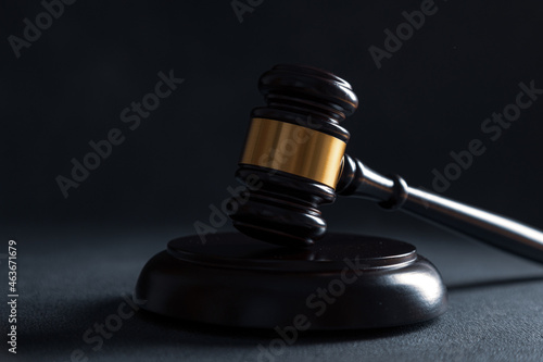Law theme, mallet of the judge on wooden desk with Lady Justice Statue. Law gavel on dark foggy background with light.