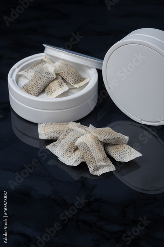 Closeup of a white swedish snus can and portion snuff pouches.