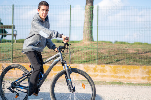 latin teenage boy with dark hair riding a bike