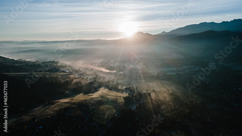 Scenic sunset at mountain range silhouette aerial view. The first or last rays of the sun. Mountains sunrise in the foggy morning above at mountain valley from drone.