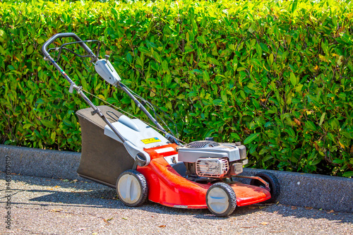 An electric lawn mower is in the parking lot. Lawn care. Apparatus for landscape design. Extra grass cleaning, golf club equipment.