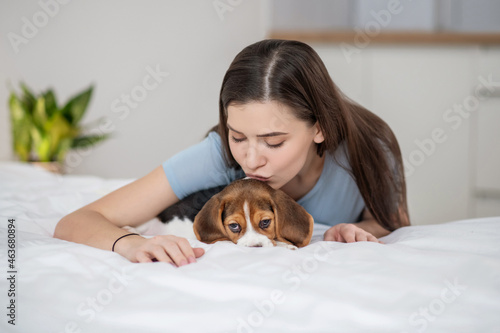 A pet owner sitting on bed and felling happy with her pet