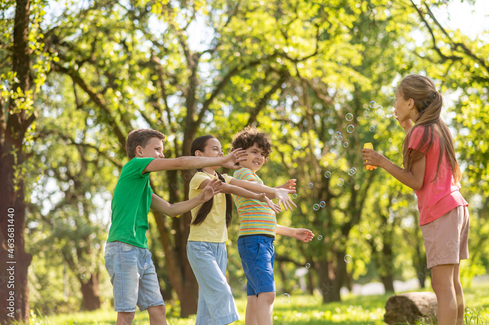 Fototapeta premium Girl with soap bubbles and friends waving hands