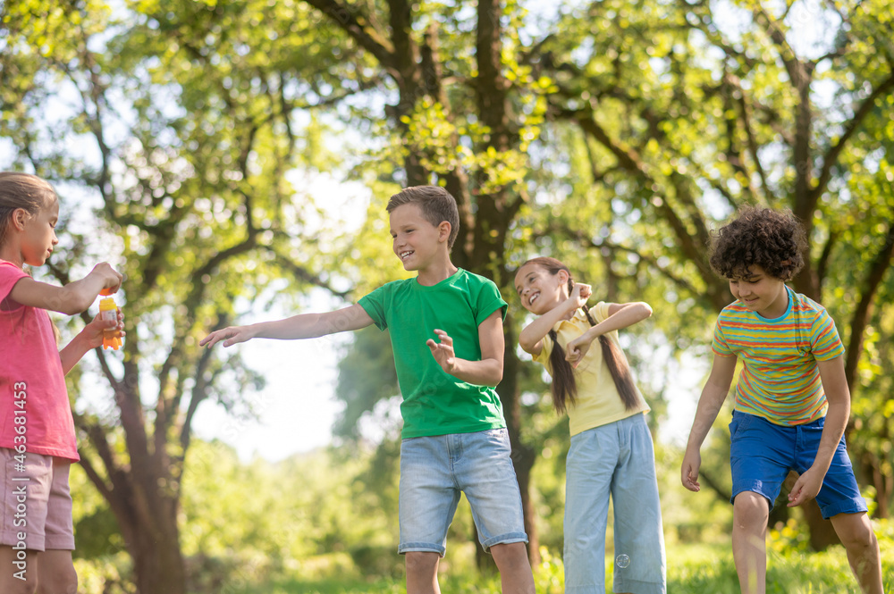 Cheerful boys and girls playing with soap bubbles