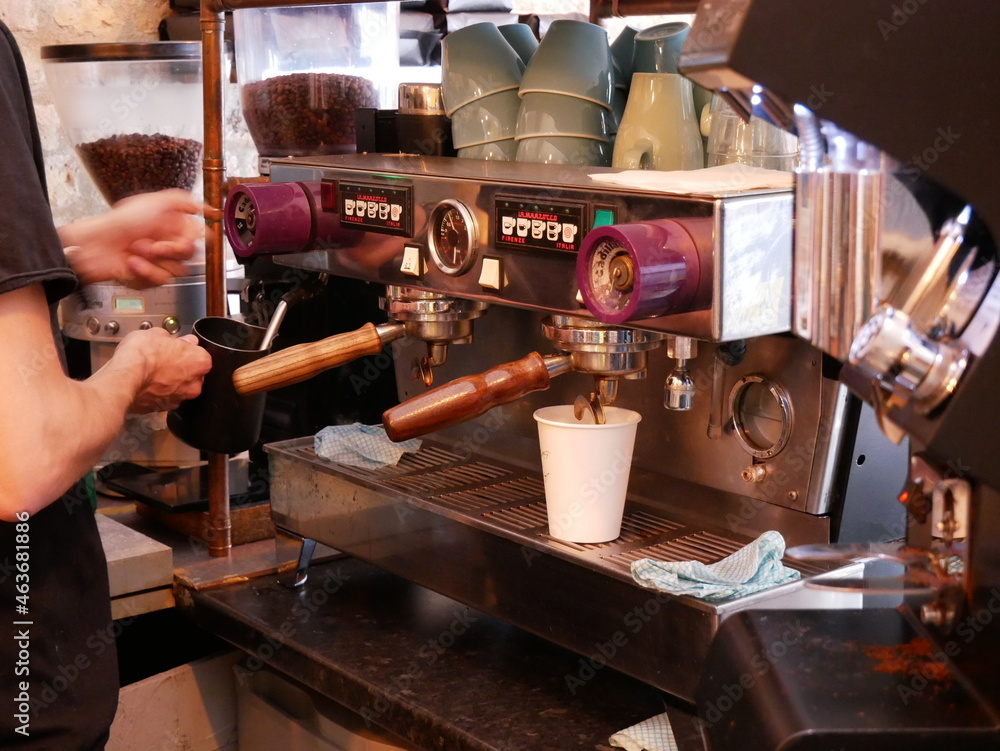 Barista using old espresso machine and pouring coffee into takeaway