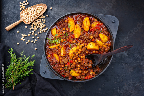 Traditional Italian ceci al sugo chickpeas with salsiccia and minced beef stew with tomato sauce and potato served as top view in a cast-iron skillet