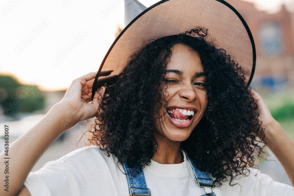 Portrait of young african american woman wearing witch halloween hat grimaces and smile. Lifestyle Halloween concept. - obrazy, fototapety, plakaty 