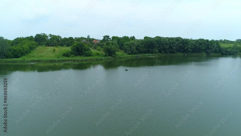 Aerial view fisherman is fishing sitting on an inflatable boat in lake. Drone wide shot adult man sailing on a boat to fish Aerial view fisherman is fishing sitting on an inflatable boat in lake. Drone wide shot adult man sailing on a boat to fish