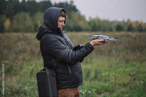 Man holding drone and remote control against field background