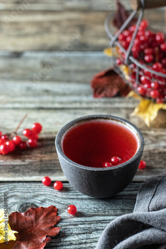 Tea with viburnum berries in a bowl, on a wooden table