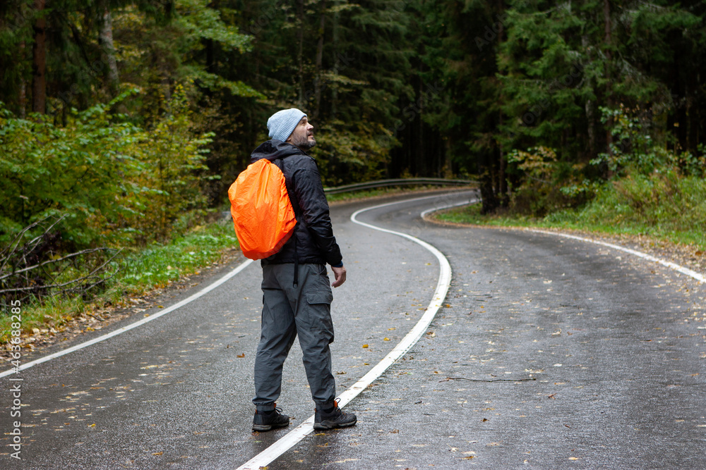 Man with orange backpack hiking in the forest Man with orange backpack hiking in the forest