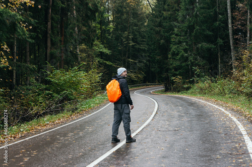 Man with orange backpack hiking in the forest