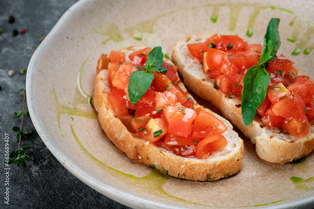 Two bruschetta with chopped tomatoes, basil and pesto sauce on ciabatta toast Two bruschetta with chopped tomatoes, basil and pesto sauce on ciabatta toast