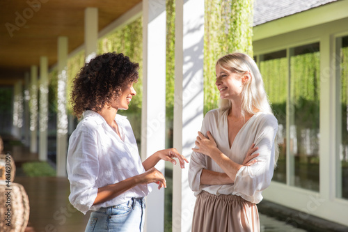 Two Women Smiling at Each Other Standing in Shaded Area
