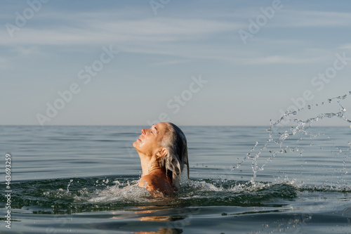Mature woman swimming in the sea and playing with water photo