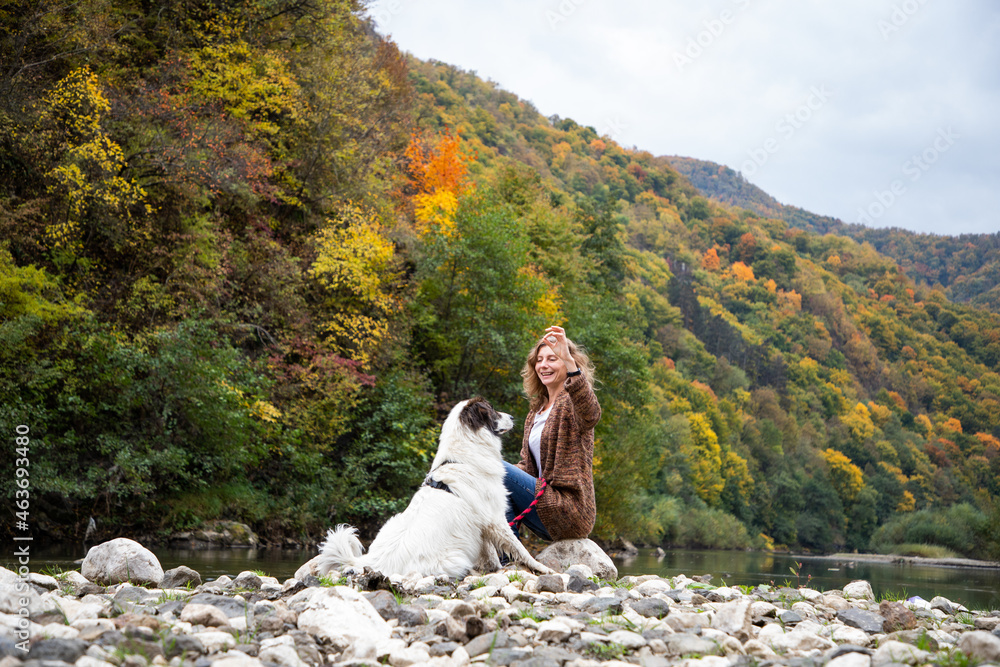 woman with dog enjoying autumn nature by the lake