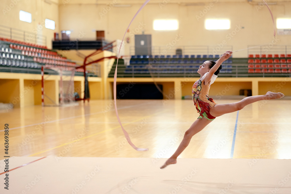 Side view of young rhythmic gymnastics athlete jumping and landing with ...