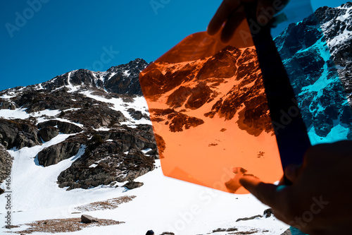 Hands holding color filter on snowy mountain landscape