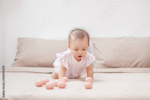portrait good-natured baby girl playing with toys on the bed in her room.