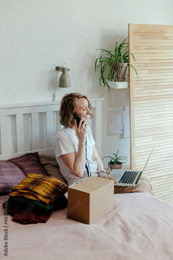 © Sergey Narevskih/Stocksy - Woman with gadgets getting rid of clothes
