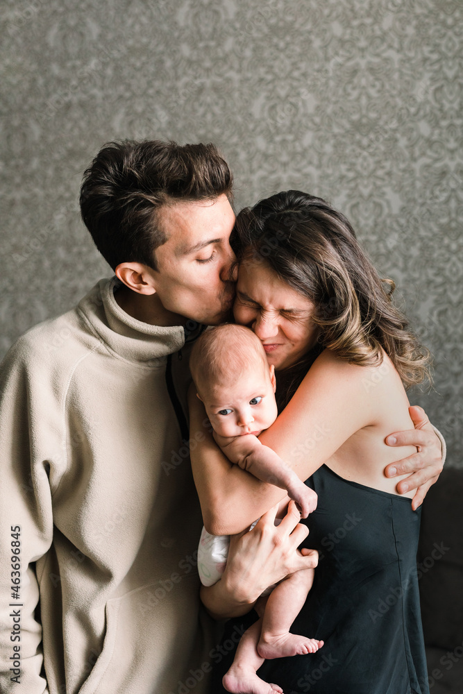 Portrait of beautiful couple with a baby in their home Portrait of beautiful couple with a baby in their home