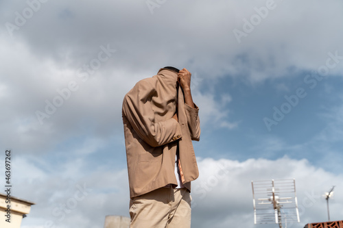 Faceless man posing hiding his face with the jacket  photo
