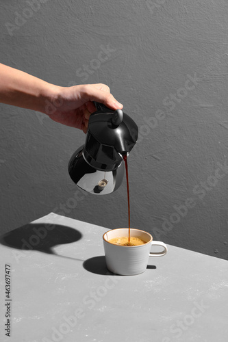 coffee poured from a flying moka into a cup isolated on gray table