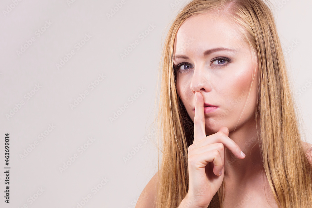 Woman asking for silence with finger on lips Woman asking for silence with finger on lips