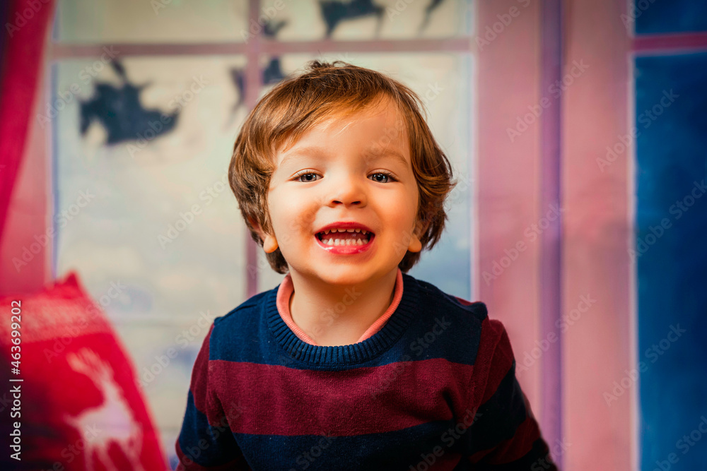 closeup of a blond little boy with a happy face and blue eyes with a christmas background closeup of a blond little boy with a happy face and blue eyes with a christmas background