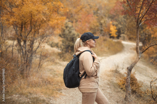 Portrait of caucasian plus size woman 30-35 years old with backpack in beige comfortable sportswear walking in the fall woods on vacations. Healthy and wellness lifestyle concept. © Evgeniya Grande