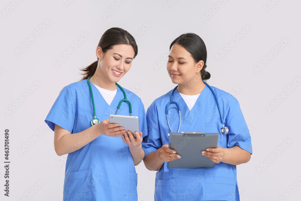 Portrait of female Asian doctors with tablet on light background Portrait of female Asian doctors with tablet on light background