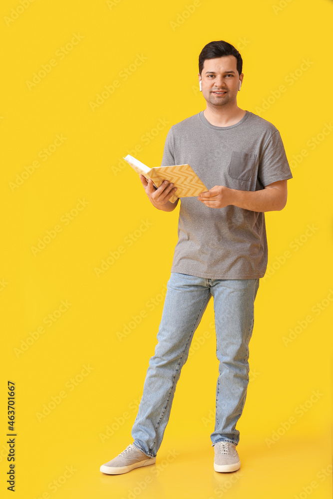 Young man with book and earphones on color background Young man with book and earphones on color background