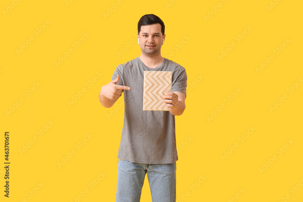 Young man with book and earphones on color background Young man with book and earphones on color background