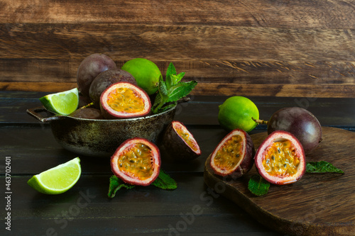 Whole and halved passion fruit or gulupa alongside lemons and spearmint on an dark aged wood background. Passiflora edulis fo. Edulis