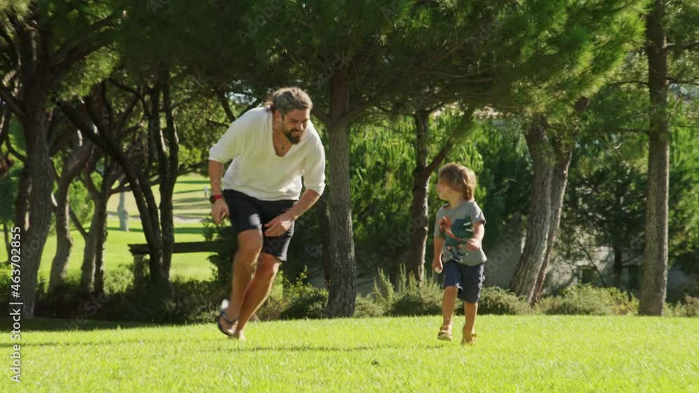 Handsome runs with cute little boy while shooting with a forest behind. Happy family time of father and son, while playing outdoor, with picturesque nature around. High quality 4k footage Handsome runs with cute little boy while shooting with a forest behind. Happy family time of father and son, while playing outdoor, with picturesque nature around. High quality 4k footage