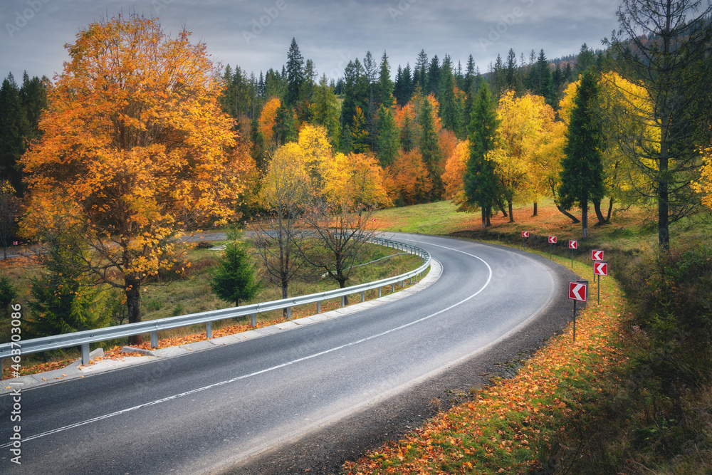 Road in autumn forest. Beautiful empty mountain roadway, trees with orange foliage and overcast sky. Landscape with asphalt road through the woods in fall. Travel in europe. Road trip. Transportation Road in autumn forest. Beautiful empty mountain roadway, trees with orange foliage and overcast sky. Landscape with asphalt road through the woods in fall. Travel in europe. Road trip. Transportation