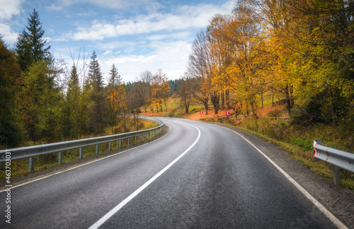 Road in autumn forest. Beautiful empty mountain roadway, trees with orange foliage and overcast sky. Landscape with asphalt road through the woods in fall. Travel in europe. Road trip. Transportation © den-belitsky