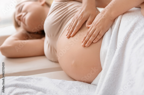 Young pregnant woman having massage in spa salon photo