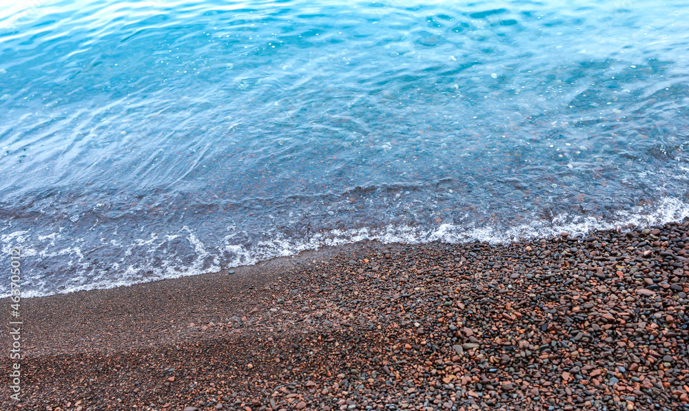 Top view of crystal clear tropical lake with wave swash over pebbles beach selective focus. Seascape view on vacations concept. Tranquility, idyllic and calmness of nature. Landscape background Top view of crystal clear tropical lake with wave swash over pebbles beach selective focus. Seascape view on vacations concept. Tranquility, idyllic and calmness of nature. Landscape background