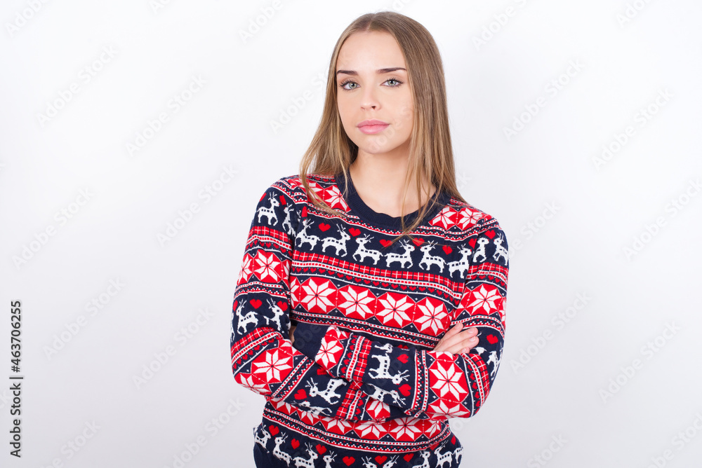 Self confident serious calm Young caucasian girl wearing christmas sweaters on white background stands with arms folded. Shows professional vibe stands in assertive pose. Self confident serious calm Young caucasian girl wearing christmas sweaters on white background stands with arms folded. Shows professional vibe stands in assertive pose.