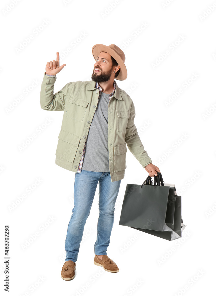 Handsome man with Black Friday shopping bags pointing at something on white background Handsome man with Black Friday shopping bags pointing at something on white background