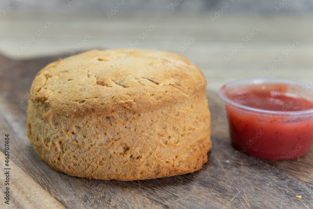 Freshly baked breakfast biscuit served with fruity jam on a wooden platter Freshly baked breakfast biscuit served with fruity jam on a wooden platter