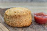 Freshly baked breakfast biscuit served with fruity jam on a wooden platter