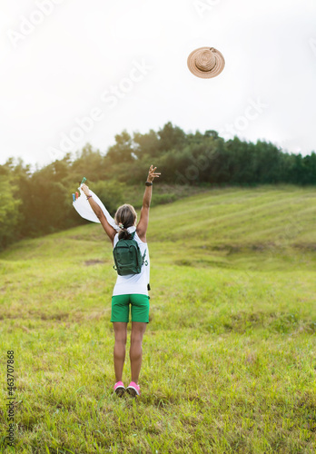 a woman in the middle of a meadow throws a hat in the air. concept of happiness and freedom.
