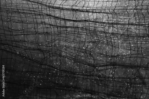 Tableau sur toile A Dark Net of Cotton Fibre, Showing a Weaved Textile of Pulled Threads and Curls with Loops of Close Detail to the Textile, on a Blurred Circular Shape Bokeh Background