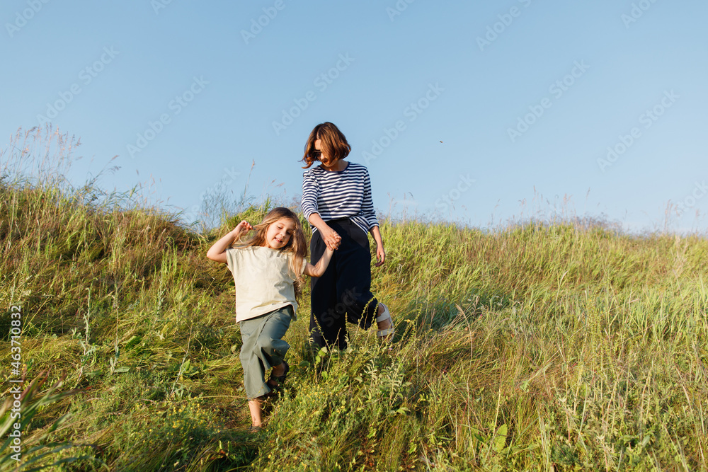 Happy girl with mother waling down the hill Happy girl with mother waling down the hill