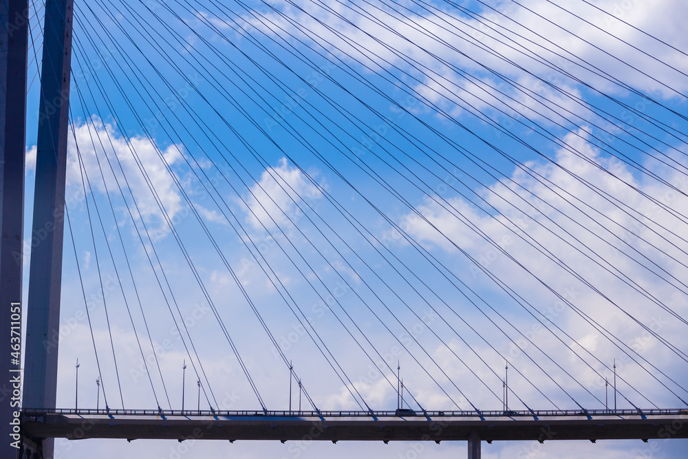 Fototapeta premium Vladivostok, 2017 - The Golden Bridge over the Golden Horn Bay in Vladivostok. Cars drive along the roadway of the suspension bridge against the background of the sea.