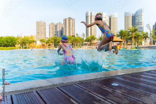 two Asian kids jumpping in the swimming pool photo