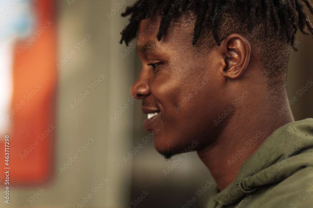 close-up portrait from side of handsome african american man smiling and looking into the camera. cheerful, positive close-up portrait from side of handsome african american man smiling and looking into the camera. cheerful, positive