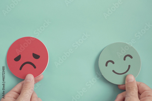 Hands holding happy and angry face paper, feedback rating , positive customer review, experience, satisfaction survey ,mood swing, mental health assessment, bipolar disorder concept